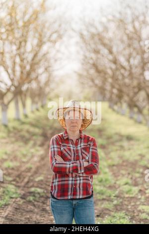 Portrait d'une agricultrice avec ses bras croisés dans le verger de noyer biologique, l'agriculture durable et le concept de produits maison, foyer sélectif Banque D'Images