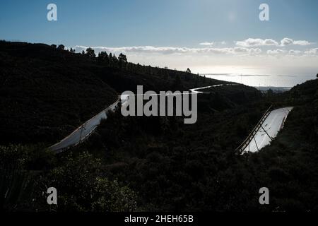 Surface de route mouillée rétro-éclairée avec vue sur la côte de Granadilla depuis Las Vegas, Tenerife, Iles Canaries, Espagne Banque D'Images