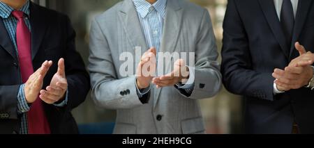 Un dirigeant ou des hommes d'affaires couronnés de succès en costume formel se claquant les mains lors de la réunion.Félicitations, accueil accueillant, atteindre les objectifs. Banque D'Images