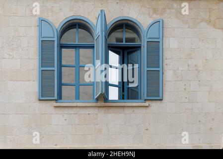 Fenêtres ouvertes du bâtiment en pierre avec cadre bleu et stores en bois bleu Banque D'Images