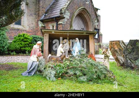 Scène de la nativité chrétienne exposée en plein air dans le cimetière d'une église traditionnelle de village de campagne en Angleterre, au Royaume-Uni, à l'heure de Noël. Banque D'Images