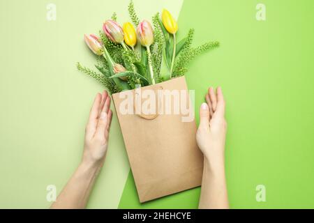 Mains de femmes et sac en papier avec fleurs sur fond deux tons Banque D'Images