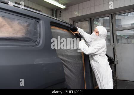 Femme de travail en costume de noisette application de ruban sur la voiture en service Banque D'Images