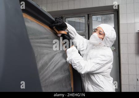 Femme de travail en costume noisette application de ruban sur la voiture dans le garage Banque D'Images