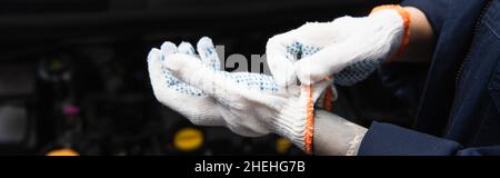 Vue rognée d'un mécanicien tatoué portant des gants dans un garage, une bannière Banque D'Images