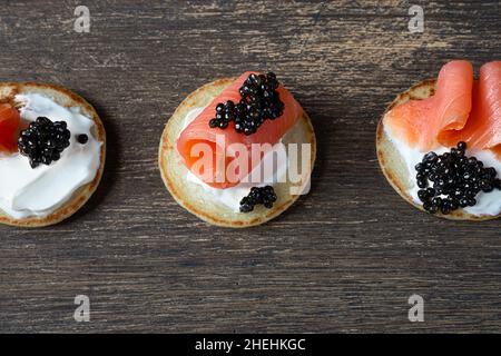 Crêpes blini avec caviar d'esturgeon noir et saumon sur une table en bois Banque D'Images