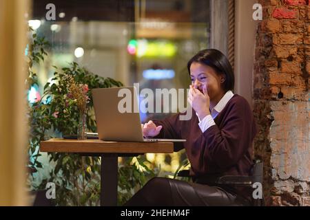 Une femme d'affaires surjoyeuse en voyage d'affaires parle à la famille par vidéoconférence après avoir travaillé dans un café rire heureux Banque D'Images