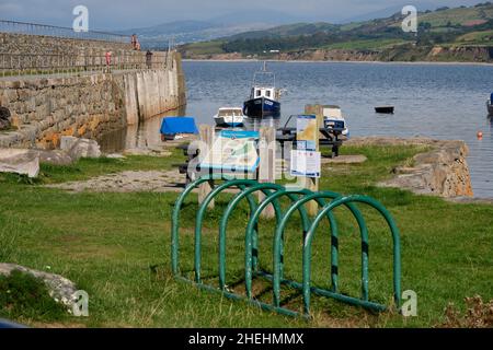 Des bateaux amarrés dans l'abri de Trefor Harbour derrière un panneau d'information pour Trefor Beach, au nord du pays de Galles Banque D'Images