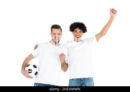 fans de sport multiethniques enthousiastes avec le ballon de football hurlant et montrant le geste de victoire isolé sur blanc Banque D'Images