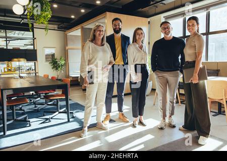 Une équipe d'hommes d'affaires heureux se tenant ensemble dans un bureau.Groupe d'hommes d'affaires souriant à la caméra tout en se tenant dans un et créatif Banque D'Images