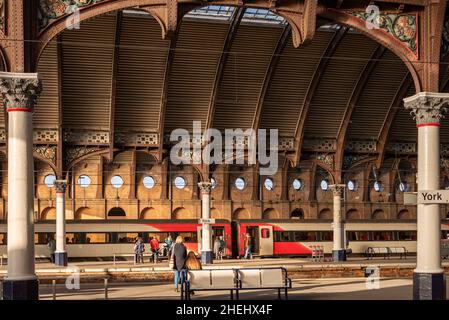 Les quais de la gare avec les passagers attendant un train.Le toit est un toit historique avec des colonnes de chaque côté. Banque D'Images