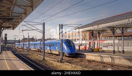 Gare historique avec trains à côté.Un signal lumineux et un pont sont à distance et des ombres sont projetées sur les plates-formes et Banque D'Images