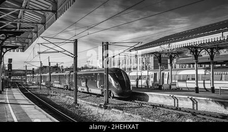 Gare historique avec trains à côté.Un signal lumineux et un pont sont à distance et des ombres sont projetées sur les plates-formes et Banque D'Images