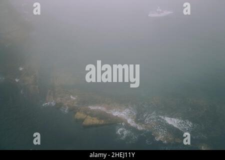 Vagues de l'océan et brouillard marin côtier autour des rochers, temps nuageux, tempête Banque D'Images