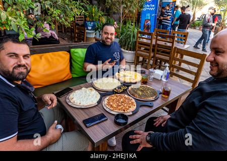 Un groupe d'hommes jordaniens mangeant Un petit déjeuner traditionnel de pains plats, Aqaba, gouvernorat d'Aqaba, Jordanie. Banque D'Images