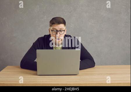 Homme caucasien avec une expression choquée, perplexe et effrayée regardant l'écran d'ordinateur portable. Banque D'Images