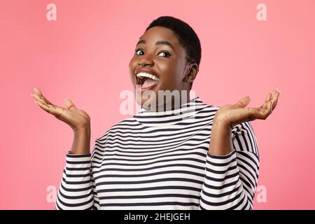 Portrait d'une femme afro-américaine excitée criant, fond rose Banque D'Images