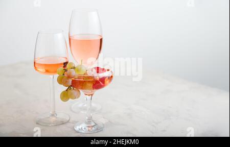 Vin de rose dans différentes verres de vin sur table blanche avec des raisins.Composition de vin sur fond béton clair. Moderne encore vie longue bannière web avec Banque D'Images