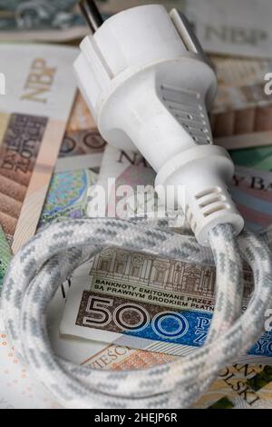 Câble électrique avec prise et de nombreux billets polonais.Hausse du prix de l'électricité en Pologne.Photo prise sous une lumière artificielle douce Banque D'Images