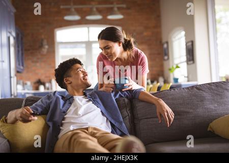 Joyeux jeune couple biracial amoureux regardant l'un l'autre dans le salon Banque D'Images