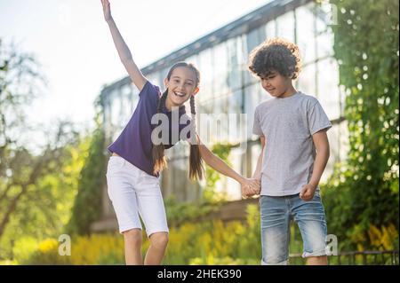 Joyeux fille à poil sombre apprenant à skate en plein air Banque D'Images