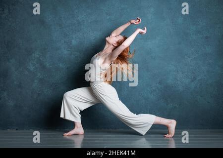 Danseuse Petitie avec des cheveux auburn rouges dansant sur fond gris Banque D'Images