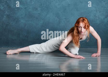 Danseuse Petitie avec des cheveux auburn rouges dansant sur fond gris Banque D'Images