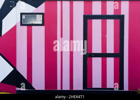 Porte et mur décorés de lignes roses et blanches. Banque D'Images