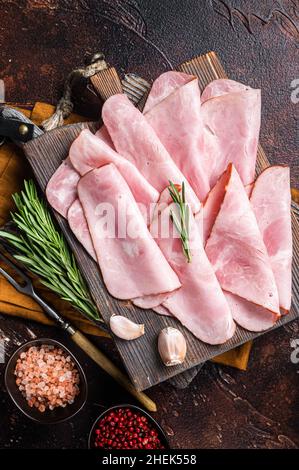 Tranches plates de jambon carré avec herbes.Arrière-plan sombre.Vue de dessus Banque D'Images