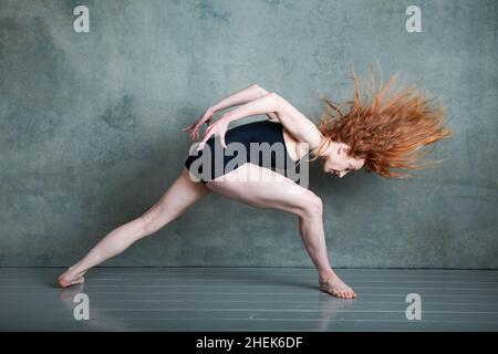 Danseuse Petitie avec des cheveux auburn rouges qui dansent en short noir et en léopard dans le studio photo Banque D'Images