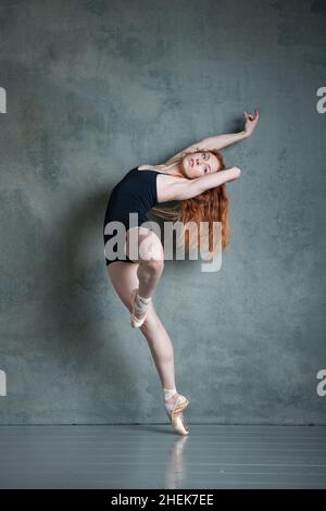 Danseuse Petitie avec des cheveux auburn rouges qui dansent en short noir et en léopard dans le studio photo Banque D'Images