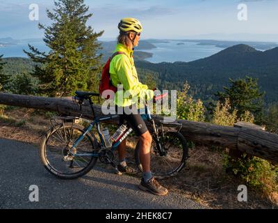 WA21052-00...WASHINGTON - cycliste bénéficiant de la vue depuis la route du Mont Constitution dans le parc national de Moran sur l'île d'Orcas; une des îles de San Juan Banque D'Images