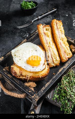 Toasts français croque monsieur et croque madame avec tranches de jambon, fromage emmental fondu et œuf.Arrière-plan noir.Vue de dessus Banque D'Images