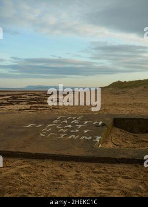 Teesside, Royaume-Uni, décembre 2018 - Un bunker de la Défense côtière ruiné et enseveli dans le sable de la Seconde Guerre mondiale, peint avec un slogan anti-science, « Flat-Earth ». Banque D'Images