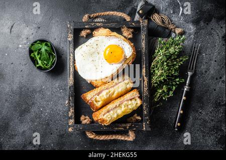 Toasts français croque monsieur et croque madame avec tranches de jambon, fromage emmental fondu et œuf.Arrière-plan noir.Vue de dessus Banque D'Images