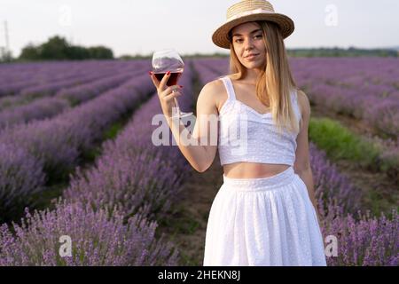 fille avec un verre de vin rouge dans un champ de lavande en provence d'été.Alcool dans la nature et aromathérapie.Repos et détente à l'extérieur.Femme de repos Banque D'Images