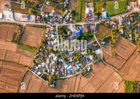 Vue aérienne du village suburbain parmi les rizières récoltées avec artère dans la campagne Banque D'Images