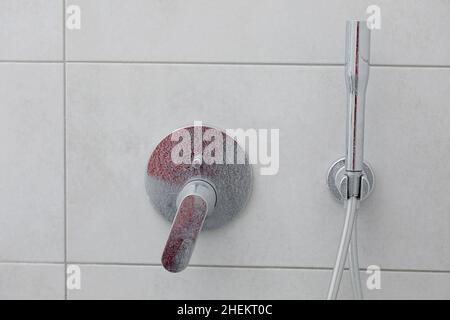 Robinet mélangeur de douche calcifiée sale, robinet avec tartre, plaque d'eau, douche chromée, photo rapprochée. Banque D'Images