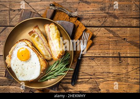 Croque monsieur et croque madame avec tranches de jambon, fromage emmental fondu et œufs, toasts français.Arrière-plan en bois.Vue de dessus.Copier l'espace Banque D'Images