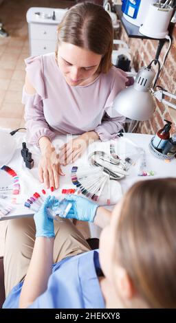 Femme client choisissant la couleur de vernis à ongles dans le salon de beauté Banque D'Images