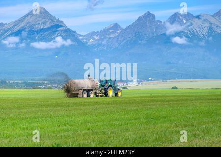 Un gros tracteur qui épandre de l'engrais pour améliorer la récolte sur les pâturages ou les champs dans les hautes montagnes de Tatra.Concept de l'agriculture terrestre . Banque D'Images