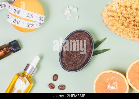 Composition Flat Lay concept anticellulite cosmétiques et traitements amincissants avec gommage au café, brosse de massage, orange et ruban de mesure Banque D'Images