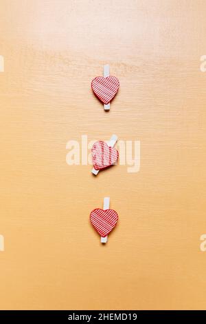 Carte de Saint-Valentin simple minimaliste, petits coeurs rouges sur une surface en bois beige Banque D'Images