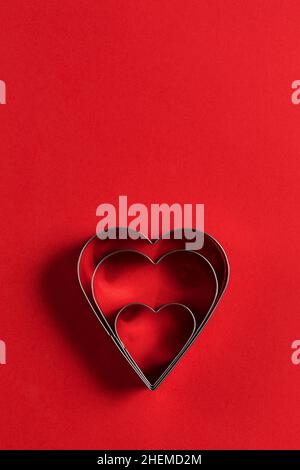 Carte de vœux minimaliste pour la Saint-Valentin, emporte-pièces en forme de coeur sur fond rouge avec de belles ombres, plat Banque D'Images