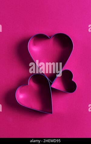 Saint Valentin carte de voeux minimaliste, emporte-pièces en forme de coeur sur fond rose magenta avec de belles ombres, plat Banque D'Images