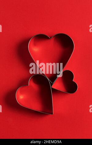 Carte de vœux minimaliste pour la Saint-Valentin, emporte-pièces en forme de coeur sur fond rouge avec de belles ombres, plat Banque D'Images