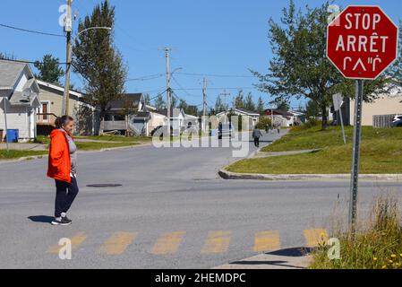 Femme crie autochtone marchant devant un panneau d'arrêt en trois langues (français, anglais, cri autochtone) Baie James, Nord du Québec, Canada Banque D'Images