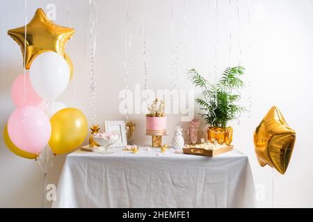 Table d'anniversaire des fêtes avec gâteau et ballons.Décoration rose et dorée Banque D'Images