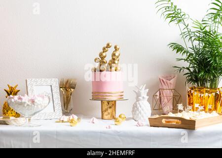 Table d'anniversaire des fêtes avec gâteau et ballons.Décoration rose et dorée Banque D'Images