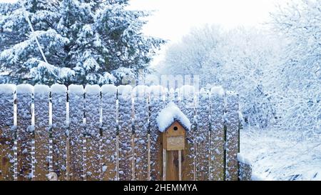 Neige abondante photo montrant une clôture avec une cabane à oiseaux recouverte de neige Banque D'Images